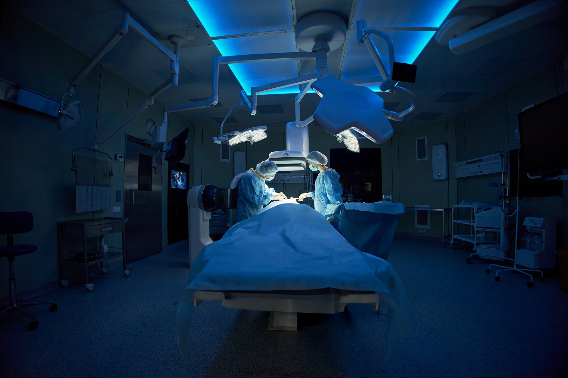 Wide angle shot of surgeons performing operation in hospital operating room with surgical lights